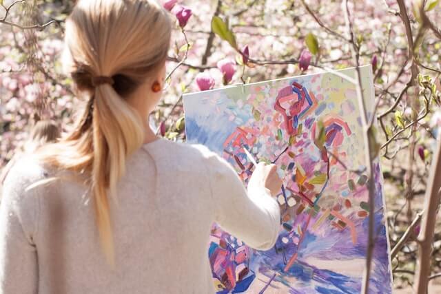 キャンバス地のパネルに絵を描く女性