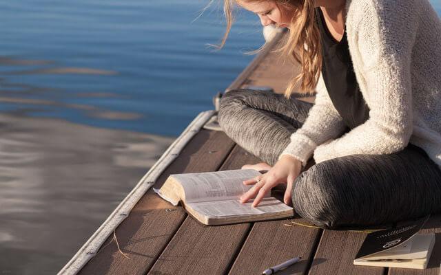 水辺で読書する女性